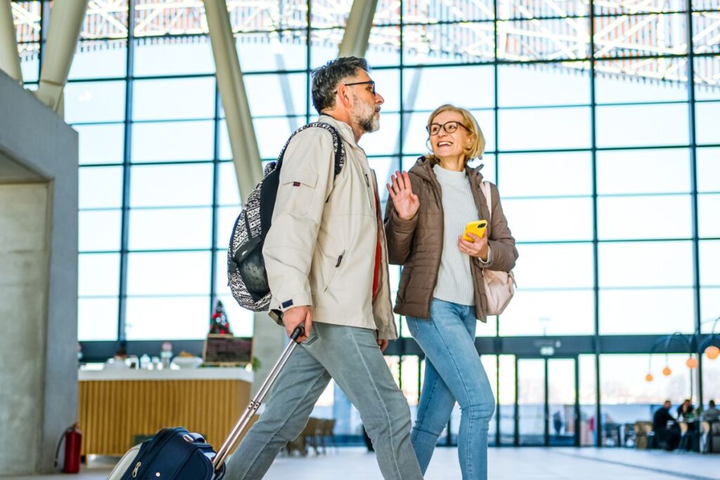 Cheerful mature couple of passengers with luggage at the train station
