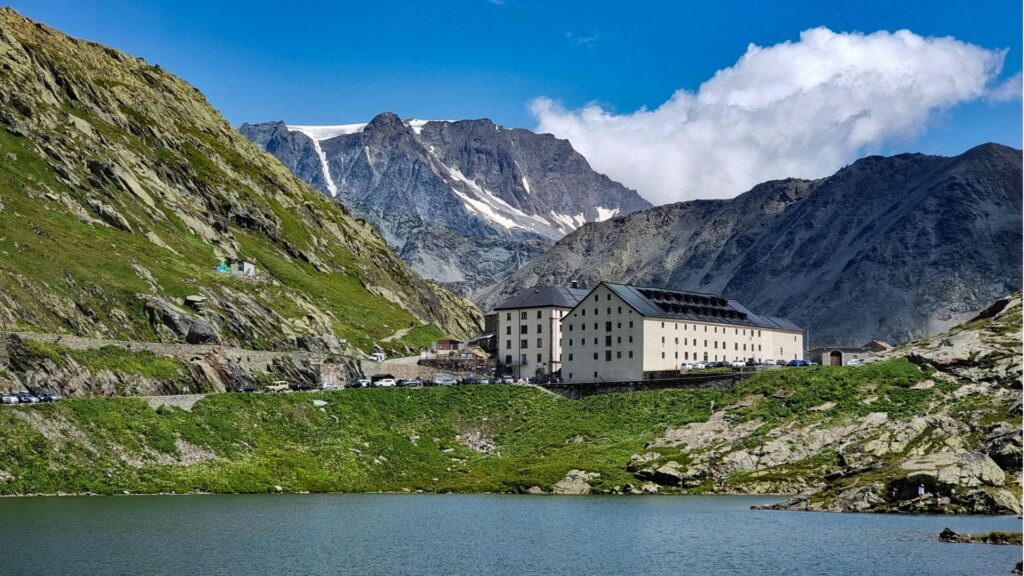 The Great St. Bernard Hospice beside its lake, with snow-capped peaks rising behind it.