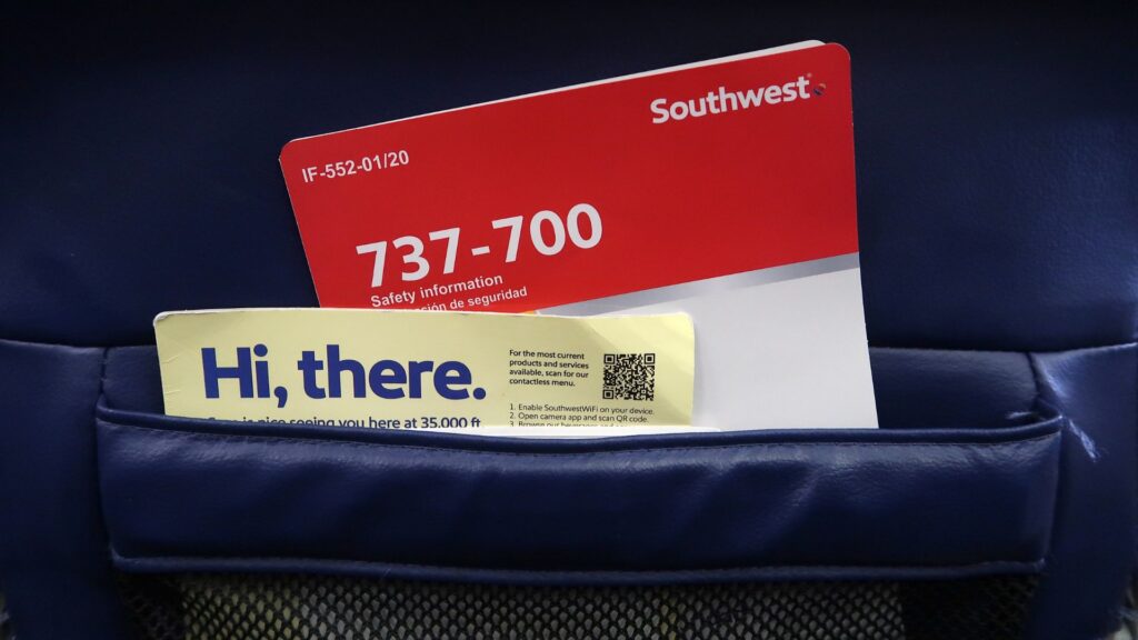 Southwest Airlines seatback pocket holds a red 737-700 safety card and a yellow “Hi, there” welcome card.