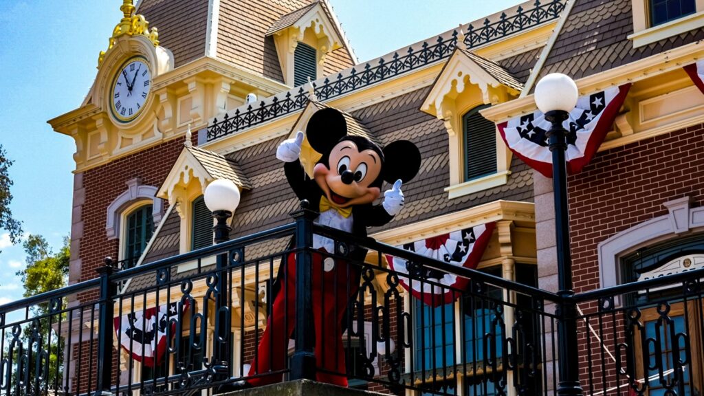 Mickey Mouse character waving from a balcony on Disneyland's Main Street, U.S.A.
