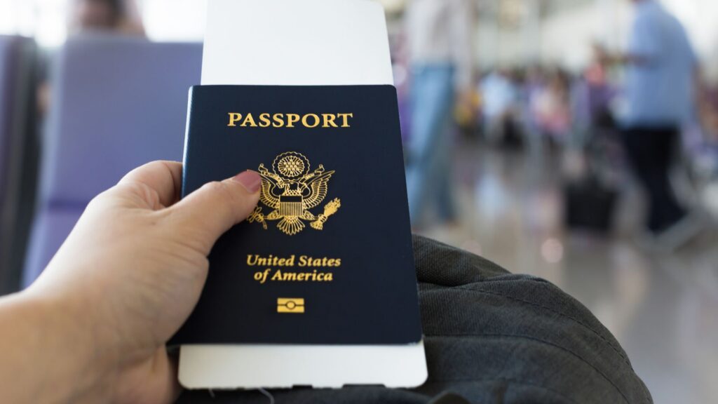 Traveler holding passport with ticket inside airport terminal.