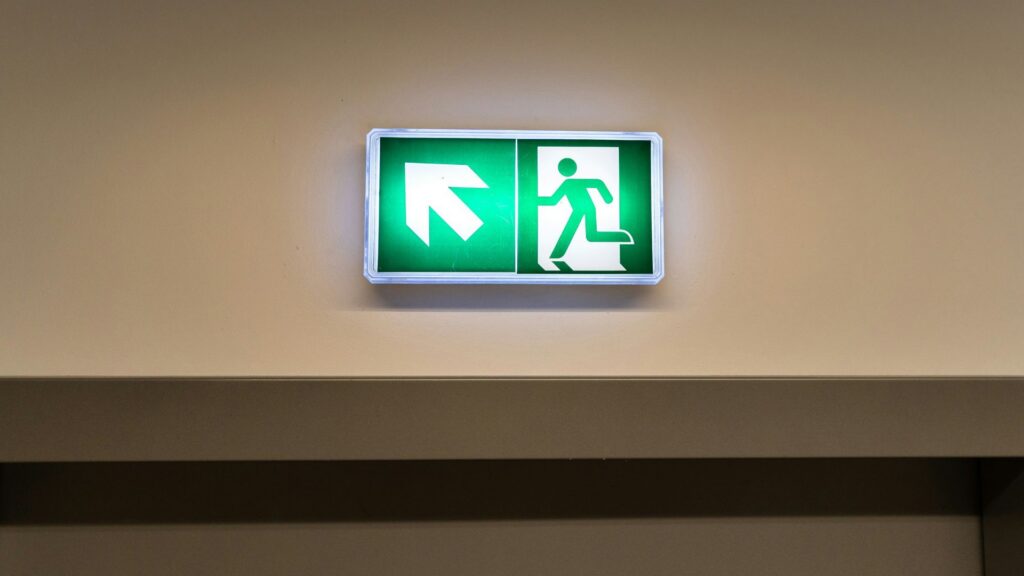 Close-up on a lit exit sign in a hotel corridor.